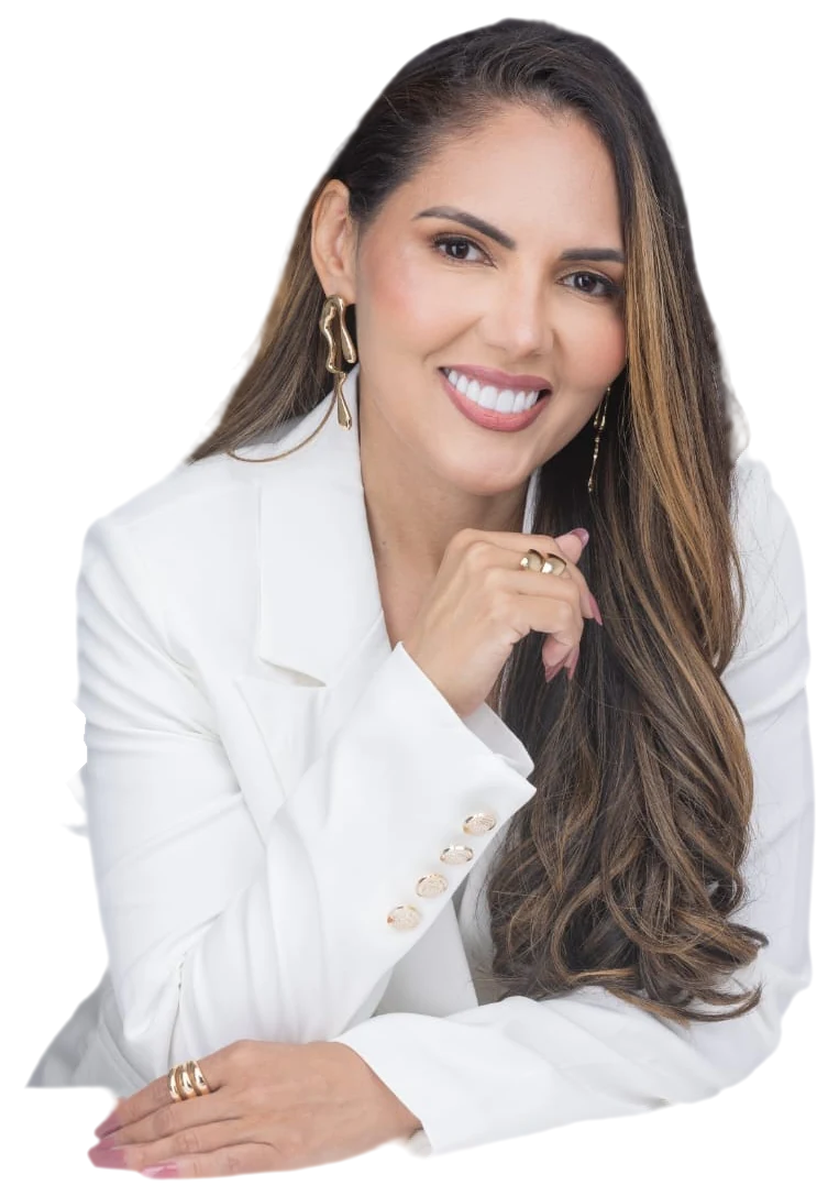 Dra. Patrícia Fonseca sorrindo, de blazer branco, com a mão próxima ao queixo
